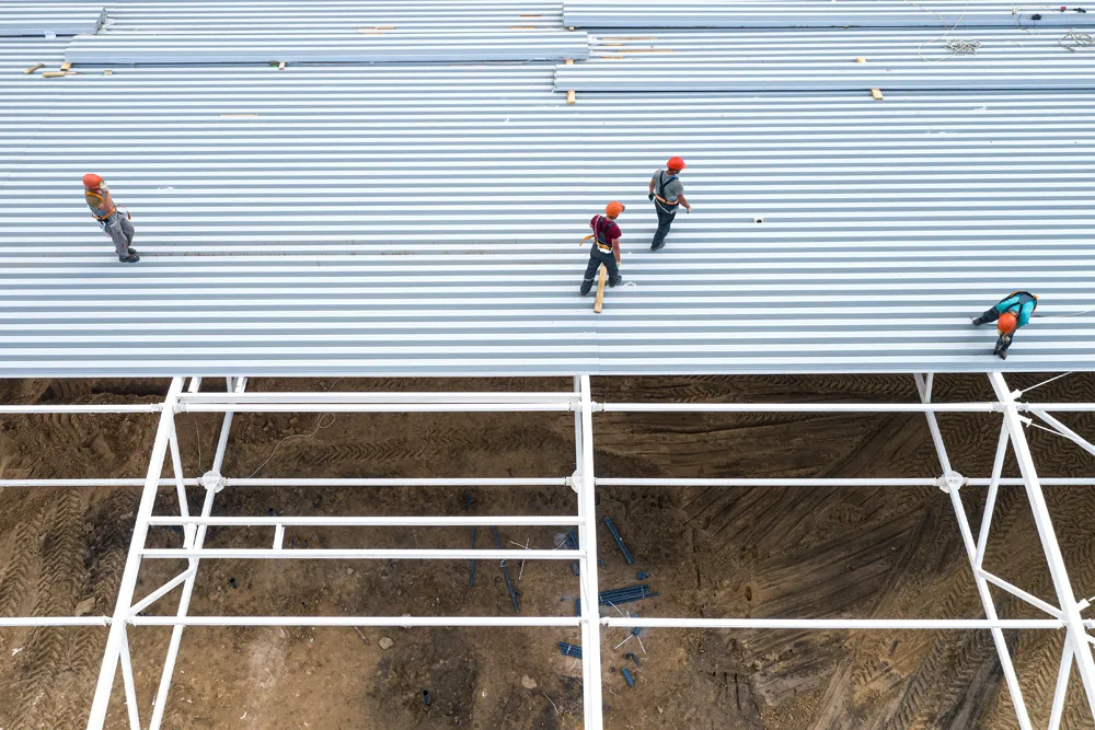 Workers install the roof of a modern frame building Top view fr