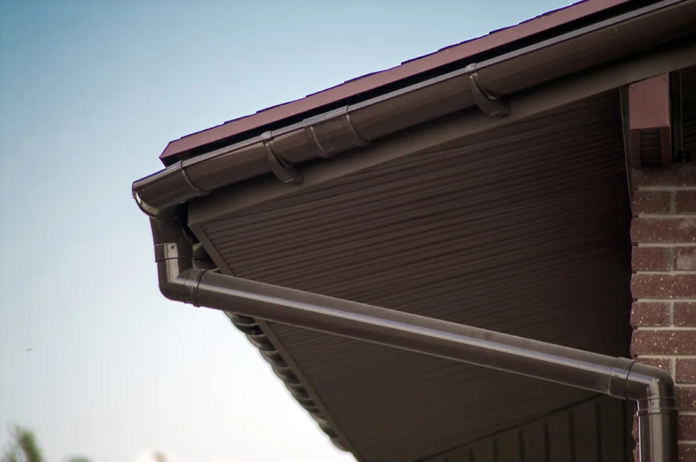 Corner of the house with new gray metal tile roof and rain gutter Metallic Guttering System, Guttering and Drainage Pipe Exterior