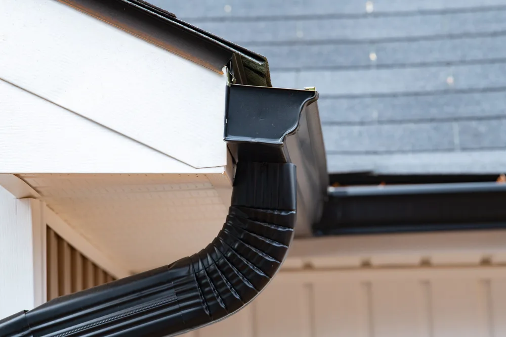 gutter with downpipe on the roof of a house