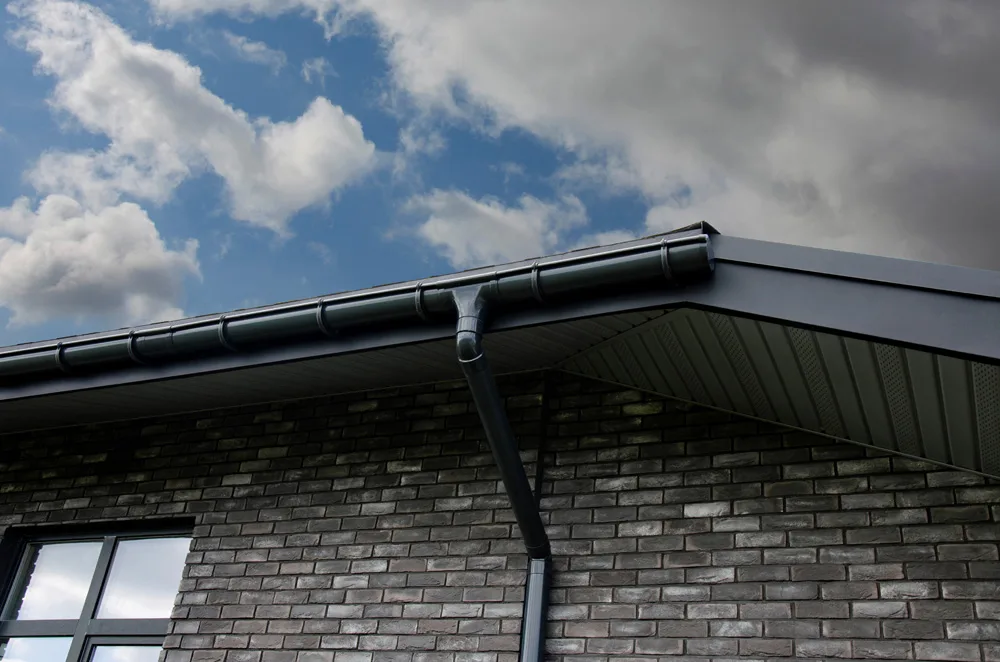 Gray plastic gutter system against cloudy sky