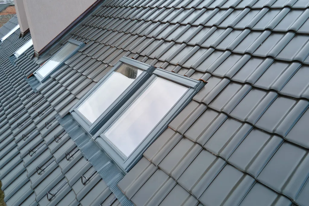 Closeup of attic window on house roof top covered with ceramic shingles Tiled covering of building